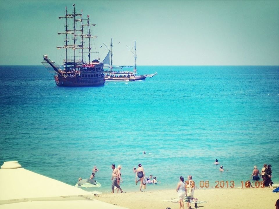 sea, water, horizon over water, nautical vessel, leisure activity, men, transportation, lifestyles, large group of people, vacations, boat, beach, person, mode of transport, blue, clear sky, sky, medium group of people, shore