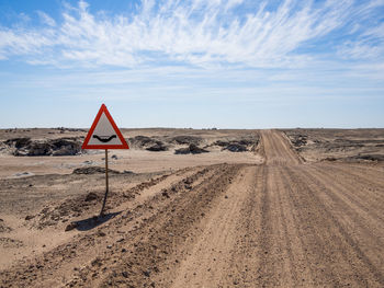 Road sign of river crossing in namib desert against sky, namibia