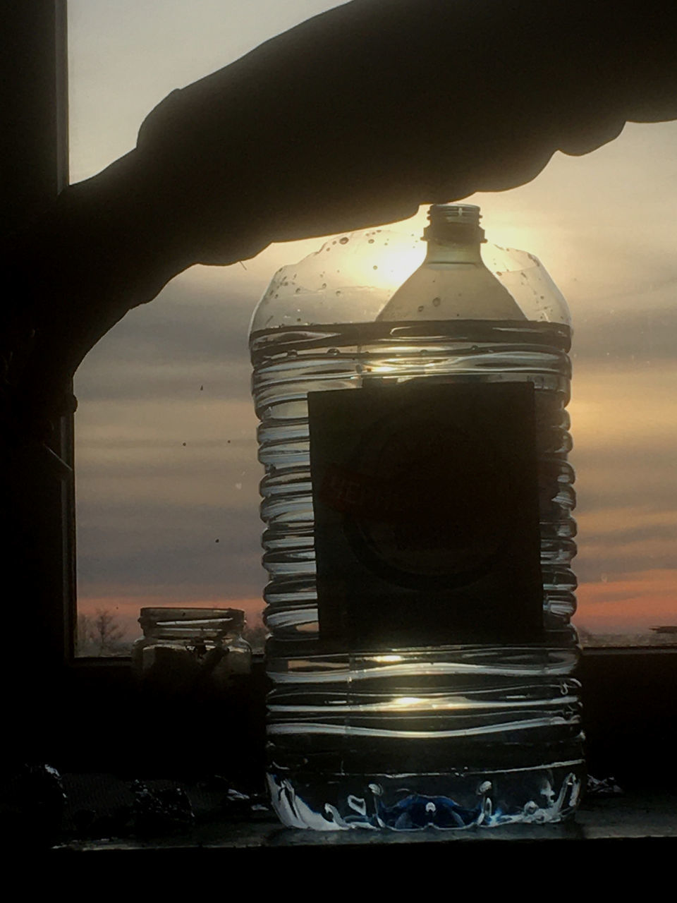 CLOSE-UP OF HAND HOLDING GLASS BOTTLE