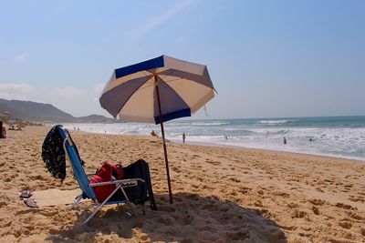 Chair on beach against sky