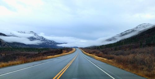 Road leading towards mountains against sky