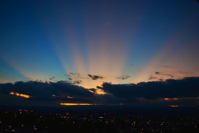 Scenic view of illuminated cityscape against cloudy sky