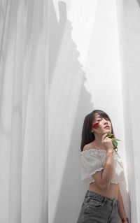 Woman holding ice cream standing against wall