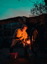 Man standing by fire against sky at night