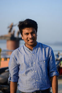 Portrait of young man standing against blue sky