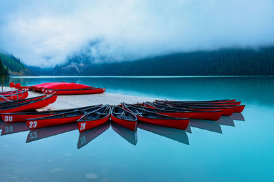 Red boat moored in lake against sky