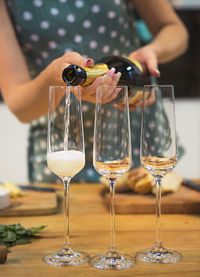 Midsection of woman pouring champagne in flutes on table