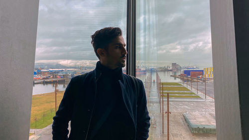 Man looking at cityscape seen through glass window