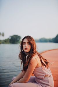 Woman looking away while sitting by river