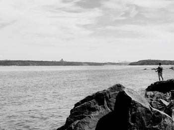 People looking at sea shore against sky