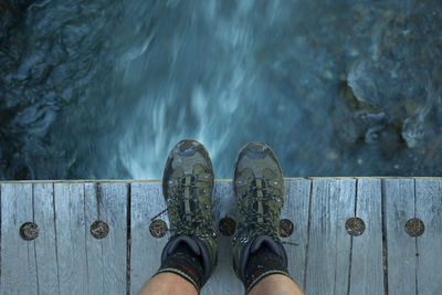 Low section of man standing over water