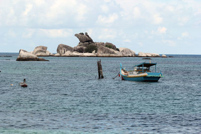 Boats in sea against cloudy sky