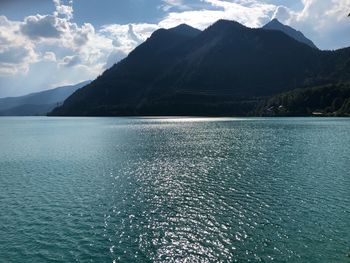 Scenic view of sea by mountains against sky