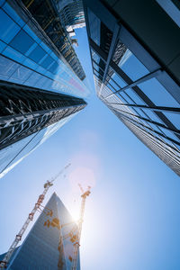 Low angle view of crane by building against clear sky