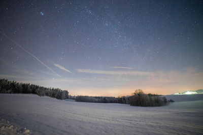 Scenic view of snowcapped field against sky at night