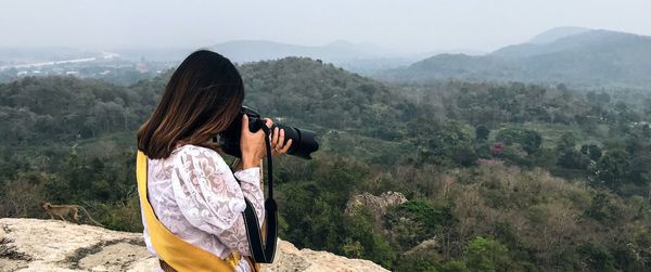 Woman photographing standing against landscape 