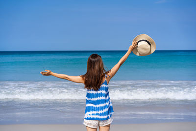 Rear view of woman walking on beach against sky
