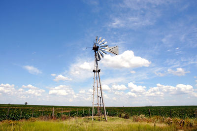 Low angle view of windmill on field against sky