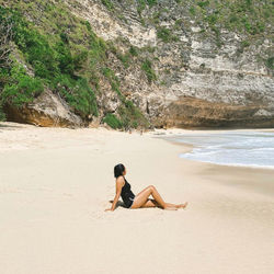 Full length of woman sitting at beach