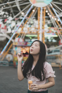 Young woman holding bubbles in amusement park