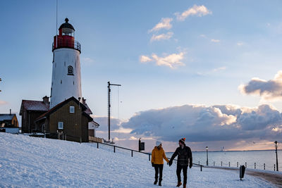 People walking on snow covered land against sky