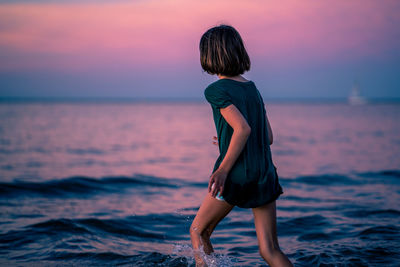 Rear view of woman standing on beach during sunset