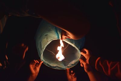 Close-up of hand holding lit candle