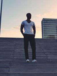 Low angle view of man standing on steps against sky during sunset