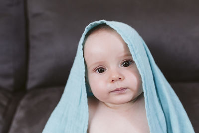 Cute baby boy wearing towel on sofa at home