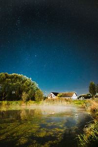 Scenic view of lake by building against sky at night