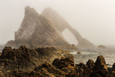 Scenic view of rocks in sea against sky