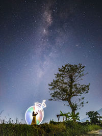 Tree on field against sky at night