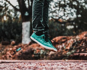 Low section of man jumping on footpath