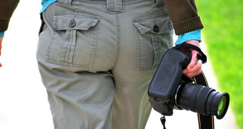 Midsection of man holding umbrella standing outdoors