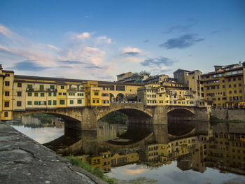 Low angle view of ponte vecchio on arno river against sky