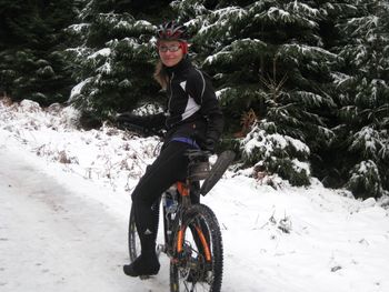 Portrait of woman sitting on bicycle over snow covered field