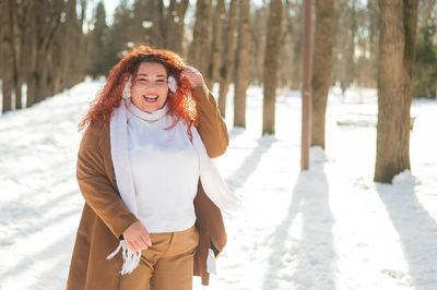 Cheerful fat caucasian woman walks in the park in winter