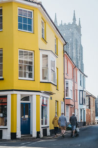 Rear view of people walking on street against buildings