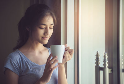 Close-up of young woman drinking coffee cup at home