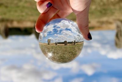 Cropped image of hand holding crystal ball with reflection