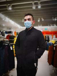 Young man wearing mask standing at clothing store