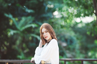 Young woman standing against tree