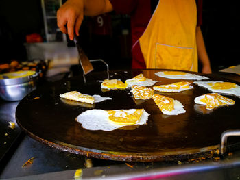 A restaurant worker is making fried eggs on a large skillet.