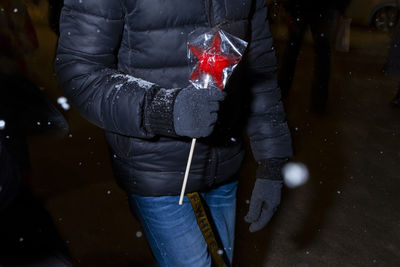 Midsection of man holding umbrella standing during winter