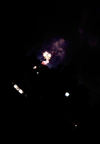 Low angle view of fireworks against sky at night