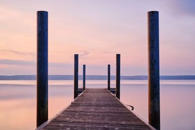 Wooden pier on sea against sky during sunset