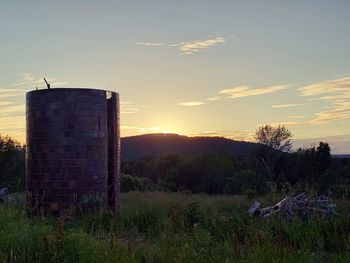 Built structure on field against sky at sunset