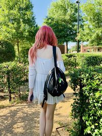 Rear view of woman standing against plants at park