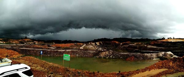 Scenic view of lake by mountains against storm clouds