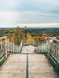 Footpath by footbridge against sky